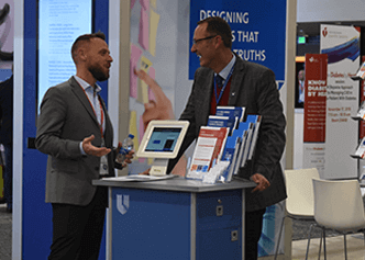 CEC operational director Matt Wilson and DCRI head of research operations Ty Rorick visit the DCRI booth during AHA 2019.