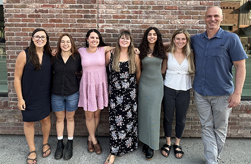 Members of the Duke-MSU STAR Program 2024 cohort and leadership smile and pose in front of a brick wall.