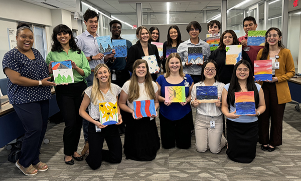 Students of the 2024 STAR Program cohort pose together while holding their finished paintings - the product of a creativity building activity.