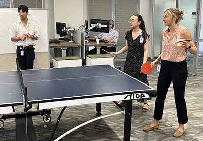 Three students laugh and play ping pong in the DCRI offices.