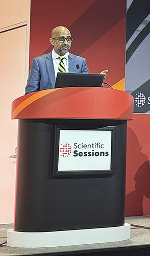 DCRI's Sreekanth Vemulapalli is shown standing at a podium during the 2024 AHA Scientific Sessions as he presents to an audience.