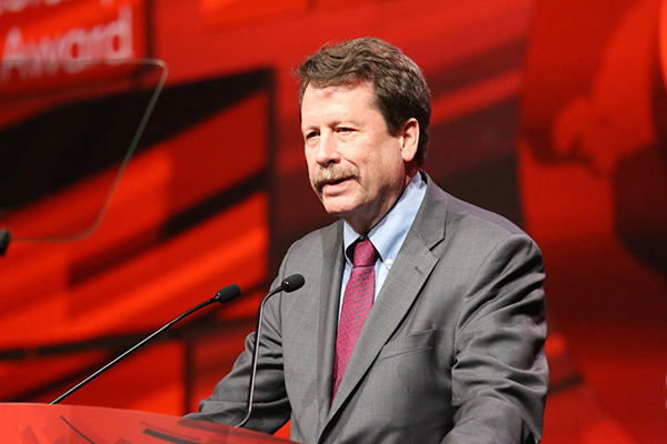 Robert Califf speaking at a podium at a conference.