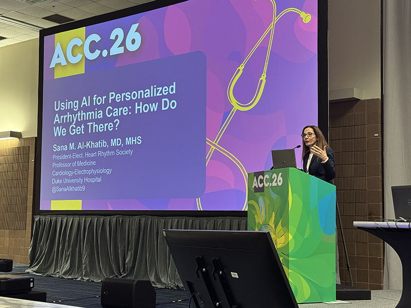 Sana Al-Khatib stands at a green podium, with the opening slide of her presentation behind her.