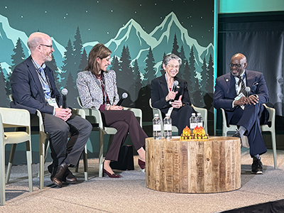 Pamela Doulas sits on a panel with three people, smiling.