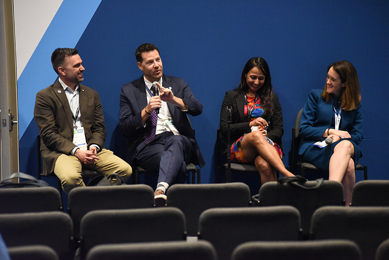 DCRI's Rob Mentz and Jennifer Rymer sit on a panel of four people talking about the challenges of balancing early career and parenthood. All panel members are smiling.