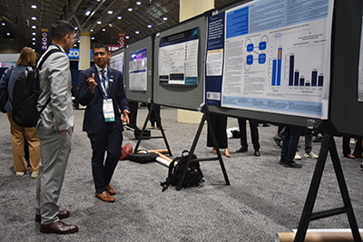 Nishant Shah stands by his poster at ACC.26 discussing the findings with a colleague.