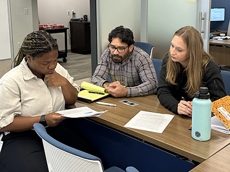 Three STAR program participants collaborate in a small-group discussion, reviewing workshop materials and exchanging ideas during a training session.