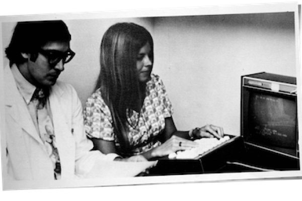 Two people in front of an old computer