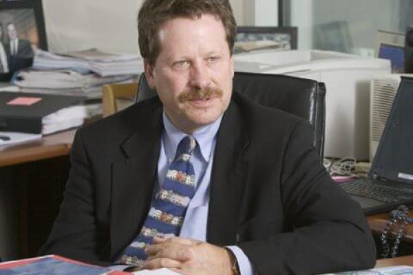 Archival image of Dr. Robert Califf, founding director of the DCRI and head of the FDA, sits at a desk speaking to someone off camera.