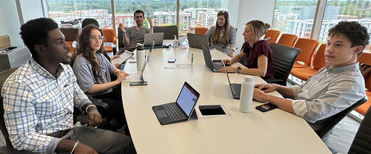 Six students of the 2024 STAR Program sit in a DCRI conference room while they discuss their work.