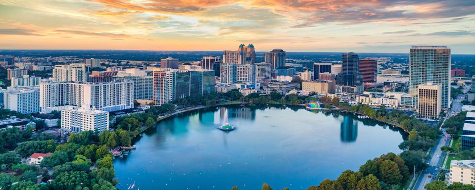 The Orlando skyline at sunset demonstrating a beautiful blue, yellow, and orange sky.